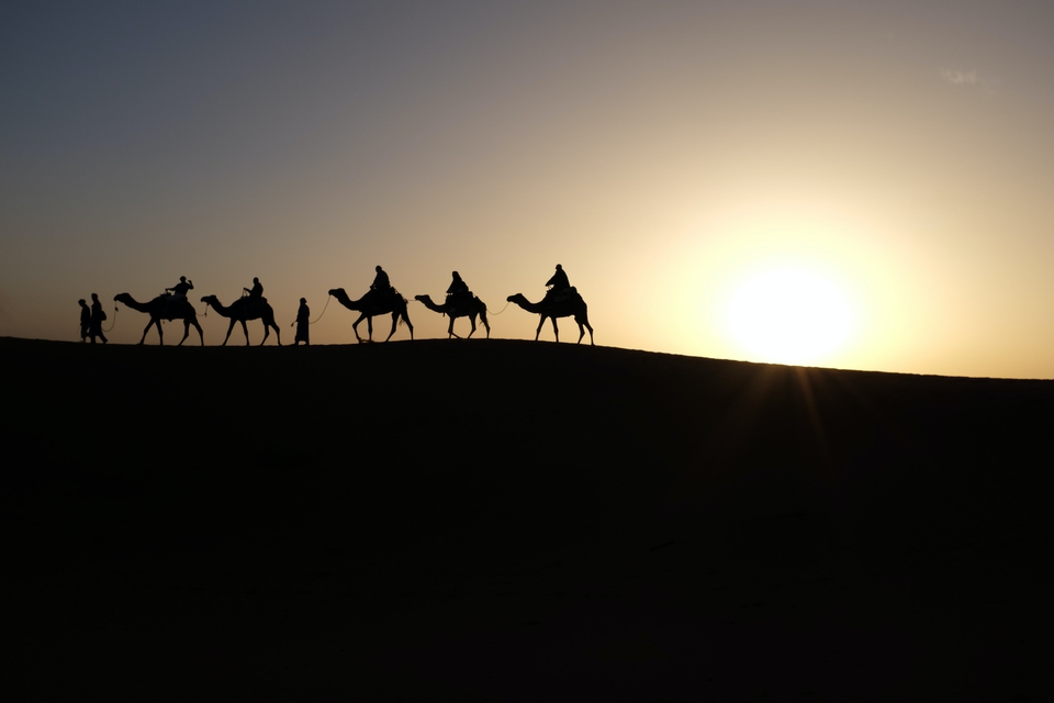 Camels and people silhouette walking in desert